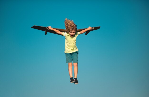 Foto menino como um piloto com asas de brinquedo contra o céu azul crianças conceito de liberdade startup