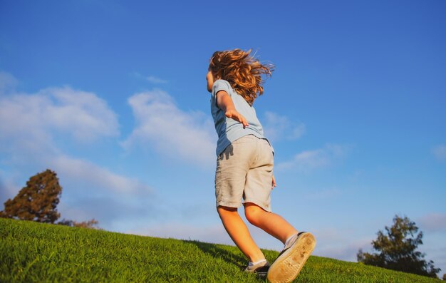 Menino correndo no prado garoto feliz correndo na bela vista traseira do campo de verão