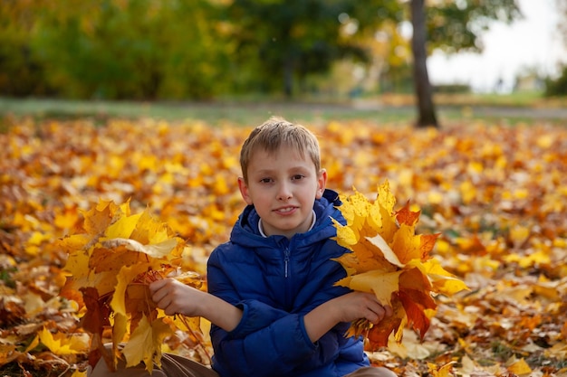 Menino criança andando no parque de outono O outono deixa o conceito de crianças