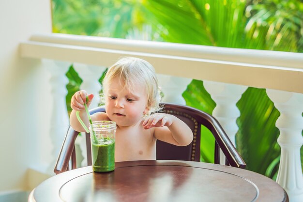 Menino criança bebendo smoothie de vegetal verde saudável - conceito de comida e bebida saudável, vegana, vegetariana, orgânica