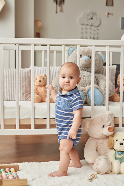 menino criança brinca brinquedos de madeira em um quarto infantil em cores brilhantes, quarto infantil estilo escandinavo