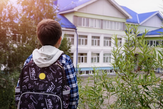 Foto menino criança com bolsa parece para a escola primária. vista traseira