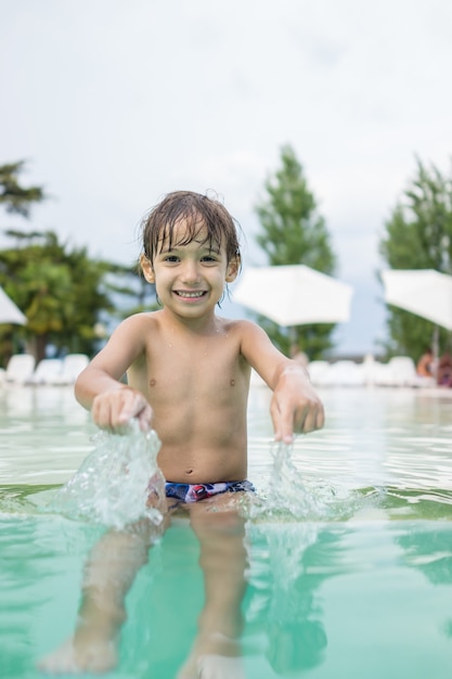 Menino criança criança espirrando na piscina se divertindo atividade de lazer