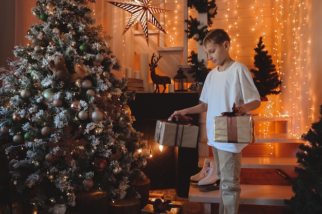 Menino criança decorando a árvore de natal em casa. família com filhos celebra as férias de inverno. as crianças decoram a sala de estar e a lareira para o natal.