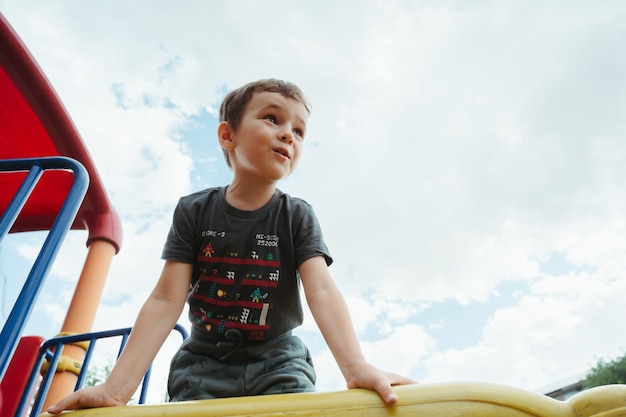 menino criança joga em um slide no playground no verão