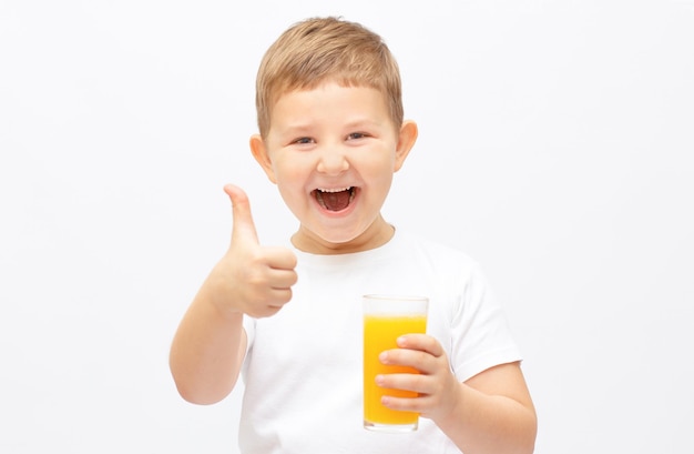 Menino criança oferecendo um copo com suco de laranja fresco e sorrindo, isolado no fundo branco