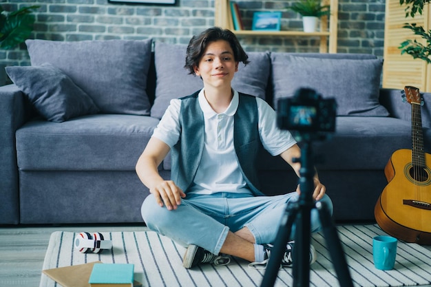 Menino criativo vlogger gravando vídeo para vlog online falando no chão em casa