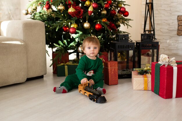 Menino da criança brincando com trem de brinquedo, árvore de Natal