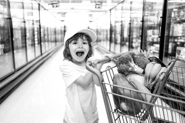 Foto menino da criança com saco de compras no supermercado criança comprando na loja do supermercado compras no supermercado