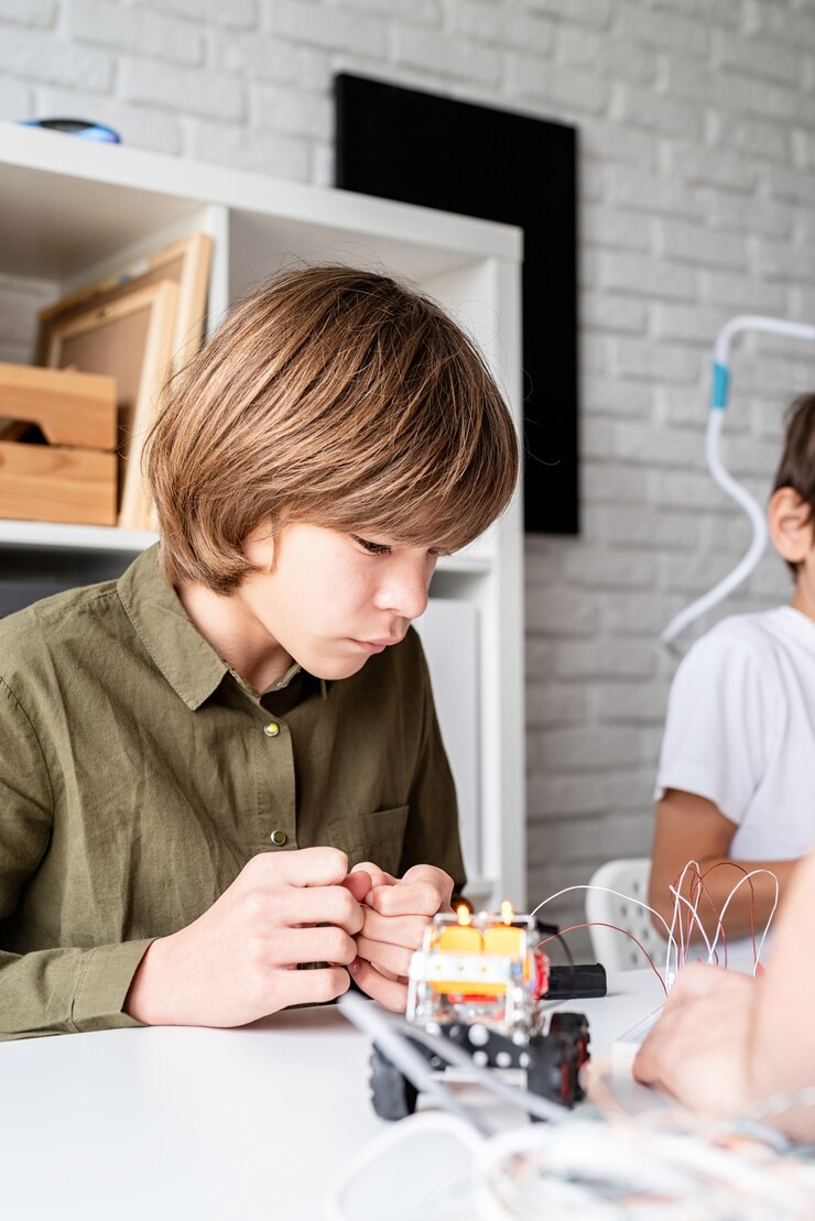 Menino de 12 anos construindo um carro-robô sentado à mesa