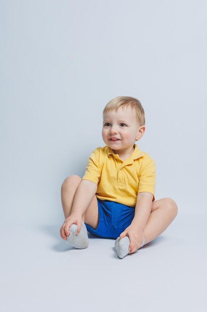 Menino de 3 anos em uma camiseta amarela e shorts azuis um menino em um uniforme esportivo