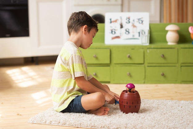 Menino de 7 anos senta no tapete e brinca com brinquedos em casa Jogos educativos