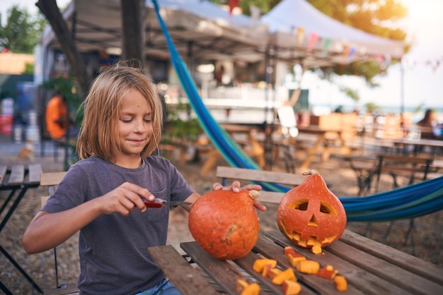 Menino de 8 anos esculpindo abóbora de Halloween