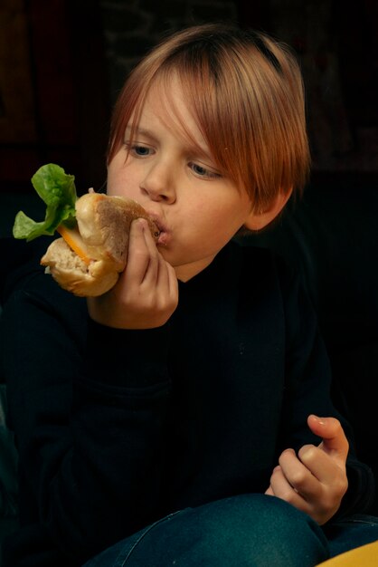 Menino de 9 anos comendo um grande sanduíche de baguete