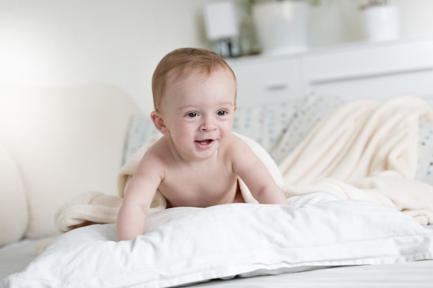 Menino de 9 meses engatinhando em travesseiros na cama