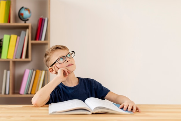 Foto menino de alto ângulo, pensando no livro lido