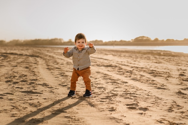 Menino de bebê fofo da criança caminhando na praia.