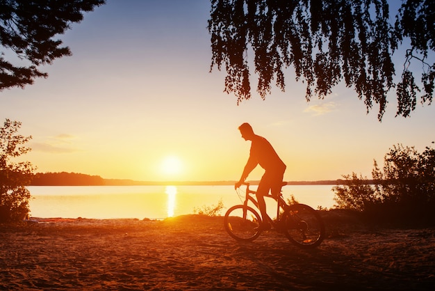 Menino de bicicleta ao pôr do sol