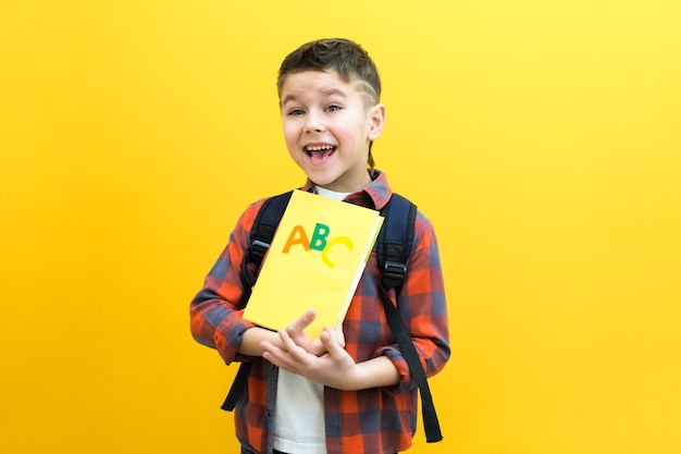 Menino de criança em um fundo de parede amarela ótima ideia o estudante sorridente feliz volta para a escola conceito de gênio vencedor de motivação de sucesso
