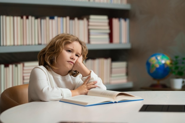 Menino de escola cansado aluno entediado na escola aluno com livro criança aluno lendo livro em uma livraria ou s