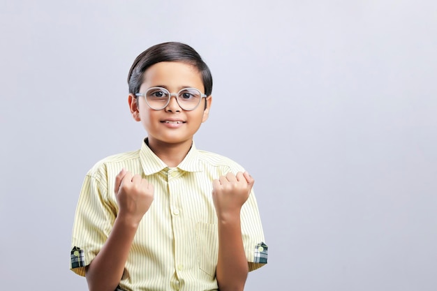 Menino de escola indiano dando o gesto vencedor no fundo branco