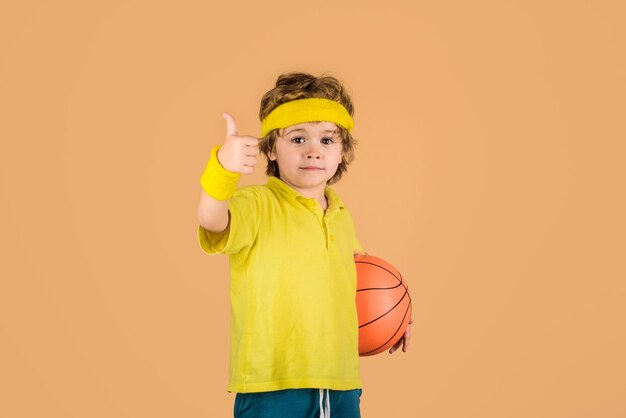 Menino de jogo de basquete de estilo de vida ativo com esporte de bola de basquete menino mostra o polegar para cima criança segura a bola