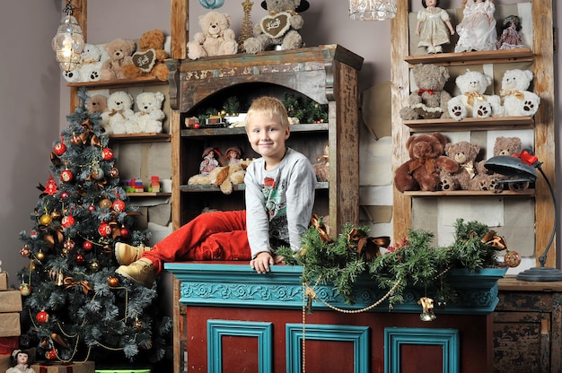 Menino de Natal ao redor da árvore de Natal com presentes e brinquedos Ursinhos de pelúcia