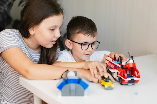 Foto menino de óculos e menina estão brincando com tijolos de construção de brinquedo coloridos