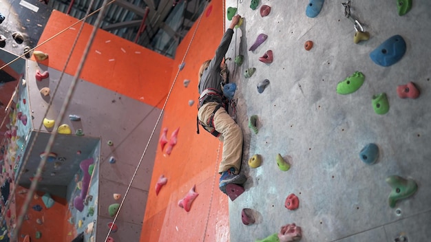 Menino de oito anos escala a parede de escalada no corredor