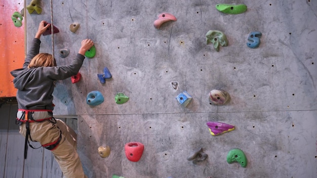 Menino de oito anos escala a parede de escalada no corredor