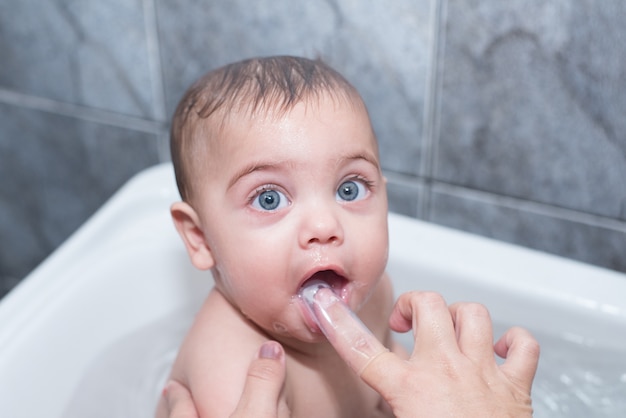 Menino de olhos azuis tomando banho na banheira