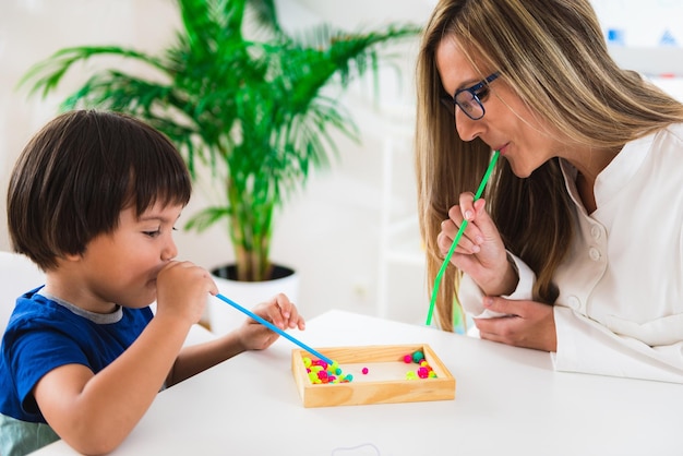 Foto menino de psicologia infantil soprando contas com palha