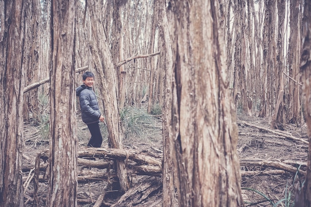 Menino de raça mista feliz asiático tween sorrindo e explorando na floresta