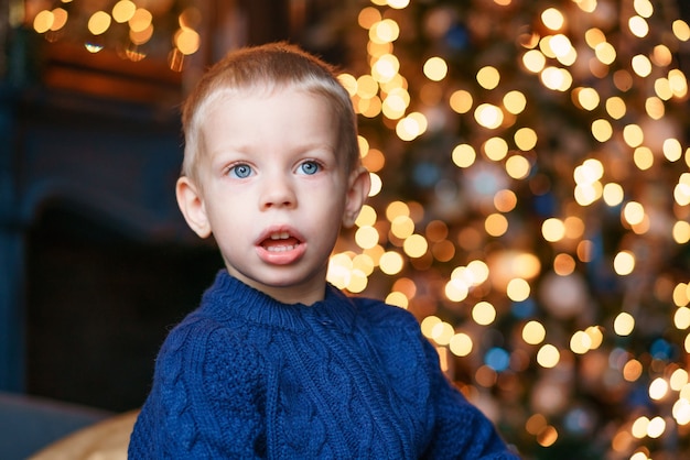 Menino de retrato nas noites de inverno contra o fundo luzes de natal animado criança azul de malha suor ...