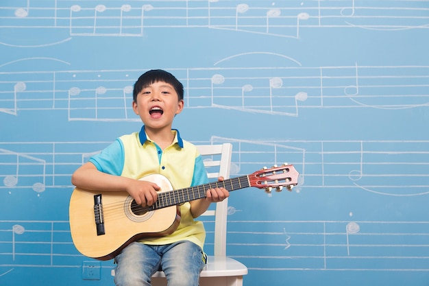 Menino de seis anos tocando violãoA partitura musical está escrita na parede