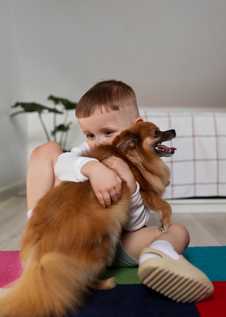 Foto menino de tiro completo brincando com cachorro dentro de casa
