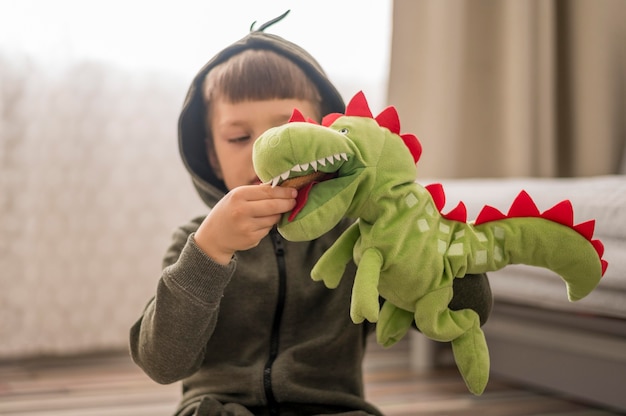 Menino de traje de dinossauro a brincar em casa.