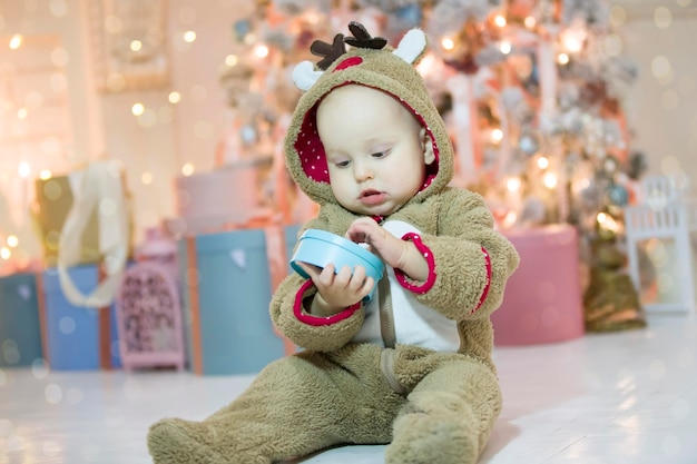 Menino de um ano vestido de veado com uma surpresa de natal