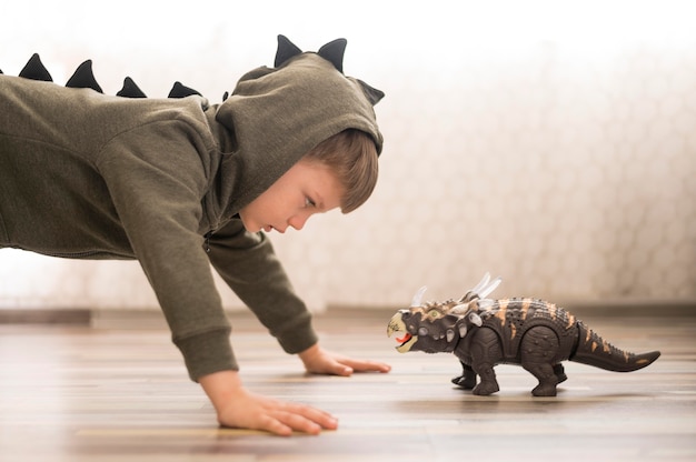 Menino de vista lateral em traje de dinossauro