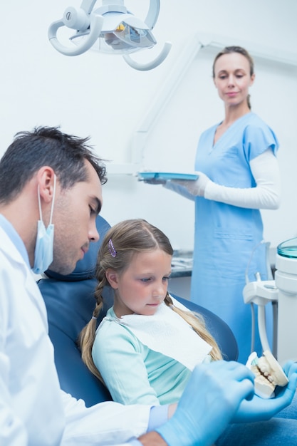 Menino dentista ensinando garota como escovar os dentes