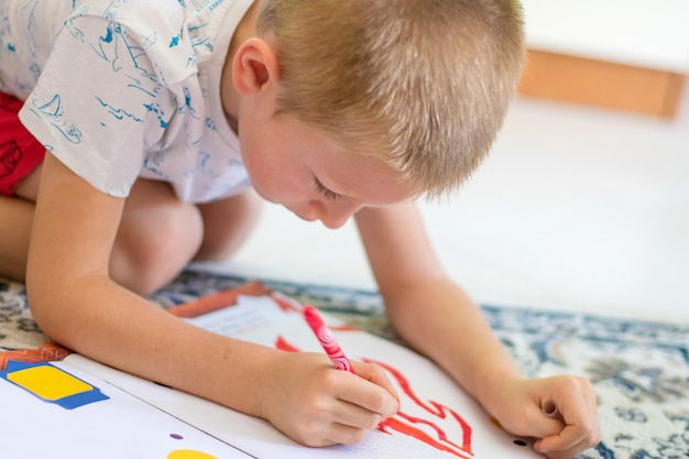 Menino desenhando no chão em um papel