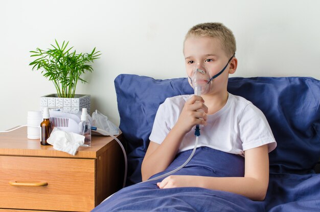 Menino doente, respirando através do nebulizador