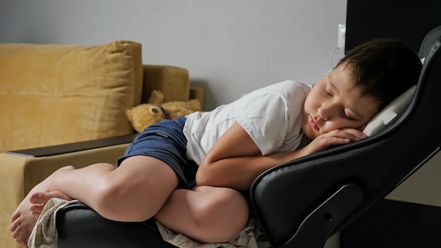 Menino dormindo docemente em uma cadeira do computador.