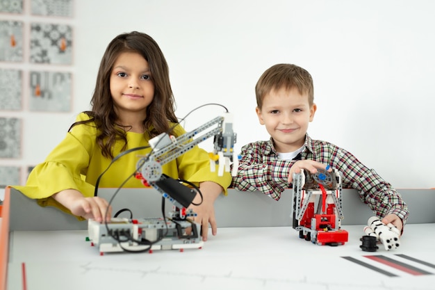 Foto menino e menina brincando com um robô feito à mão. projetos de robótica diy, diversão e desenvolvimento, lazer depois da escola.