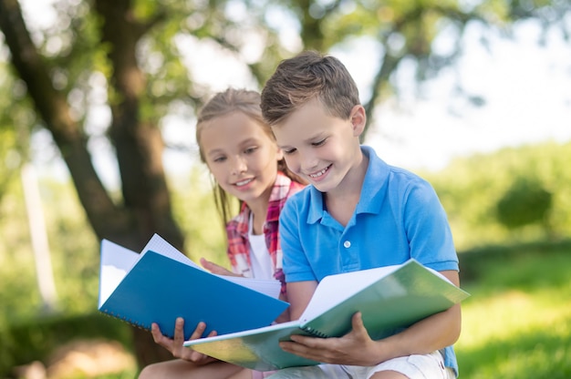 Menino e menina com cadernos no parque