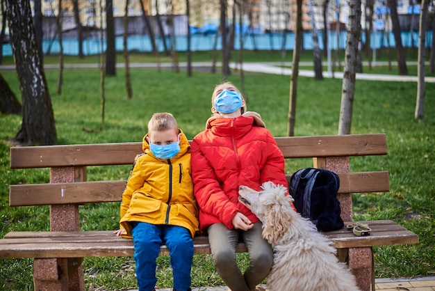 Menino e menina com máscaras médicas no parque primavera