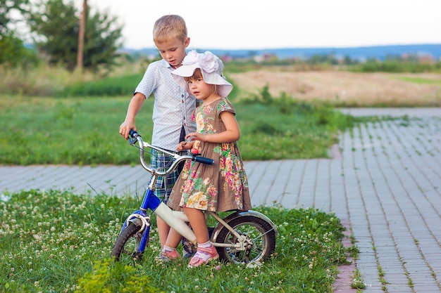 Menino e menina em bicicleta brincando ao ar livre em um dia ensolarado de verão