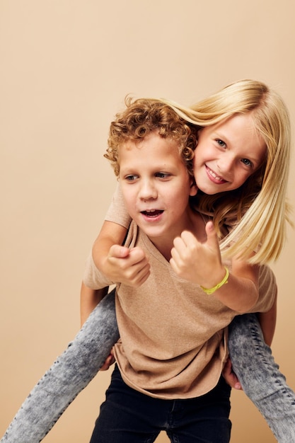 Menino e menina em camisetas bege posando para se divertir infância inalterada