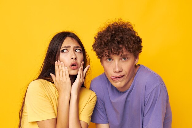 Menino e menina em camisetas coloridas posando amizade divertida fundo amarelo inalterado