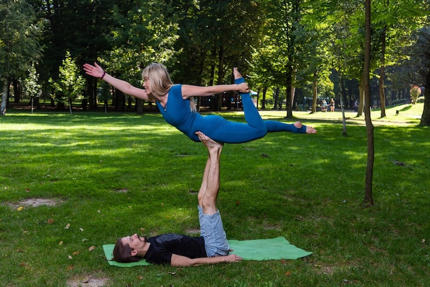 Menino e menina fazendo acro yoga ao ar livre no verão em parque público